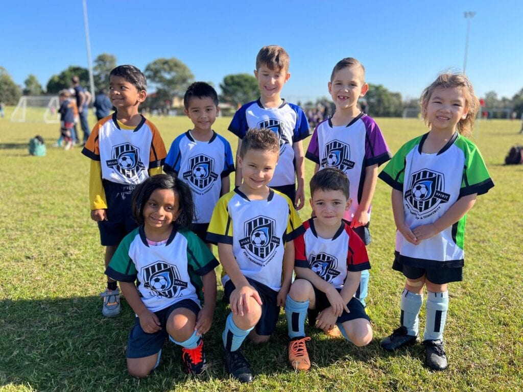 Young MiniRoos players smiling on the field